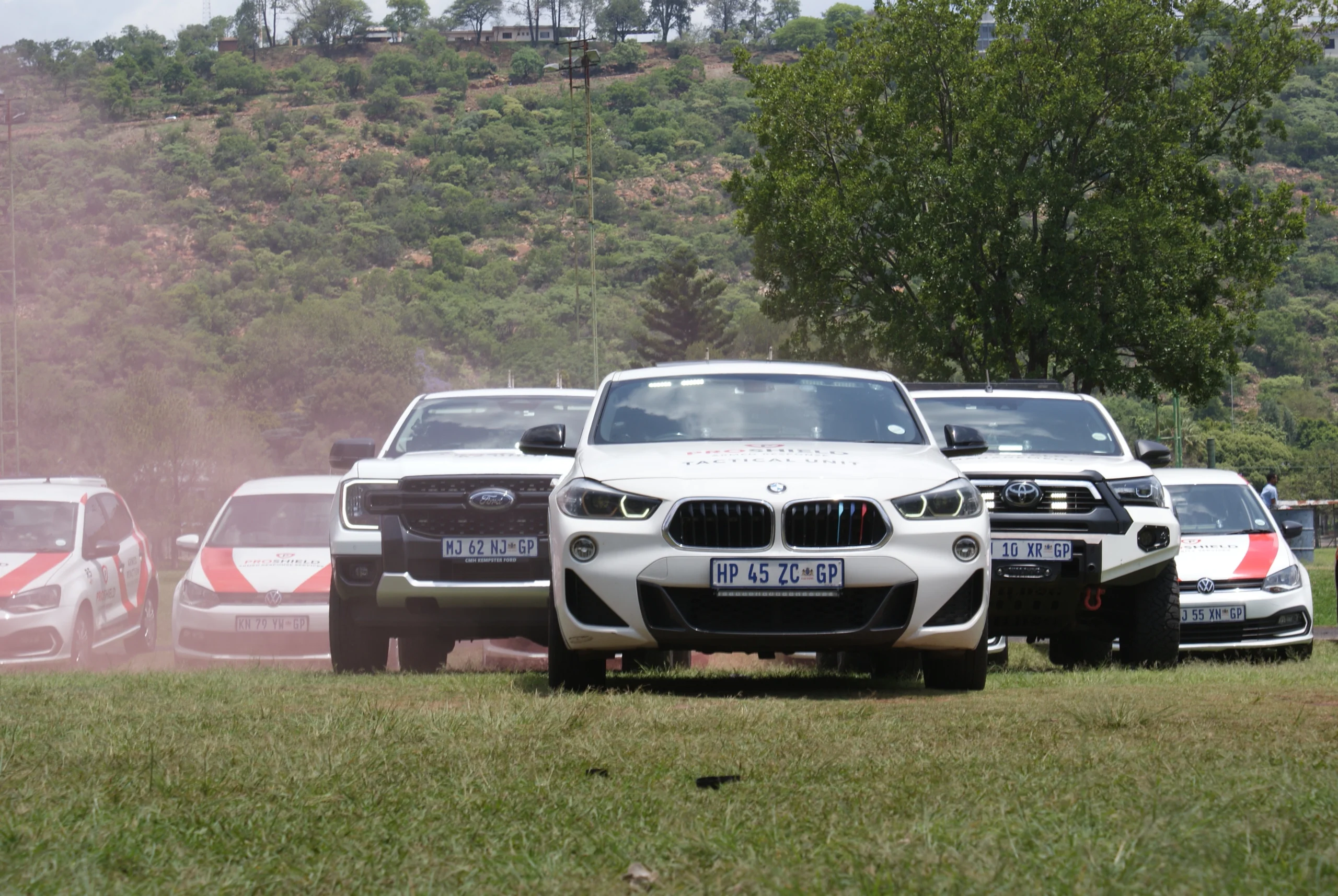 Proshield Security Vehicle Fleet standing in a field, showing their cars.